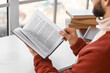 © Pixel-Shot - Young man reading book at table near window, closeup