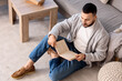 © Pixel-Shot - Handsome young man reading book on floor at home