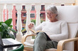 © luciano - Relaxed senior woman enjoying a peaceful moment reading a book on a balcony sitting comfortably in a lounge chair.  Lifestyle that reflects retirement, leisure, and wellbeing