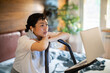 © Davor - Woman on exercise bike watching online workout at home