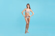 © New Africa - Beautiful woman in stylish swimsuit posing on light blue background