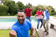 © wavebreak3 - Diverse male friends celebrating in backyard pool area, holding beer bottles, showing face paint