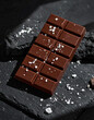 © Lumina Studio - Tableta de chocolate oscuro con sal sobre piedra volcánica