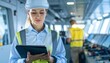 © Borayat - A woman in a hard hat and safety vest uses a tablet on a ship's bridge