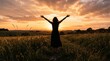 © Stock Haven - woman in silhouette with arms raised at sunset in field