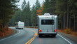 © miss irine - Two campers drive on paved road through forest with pine trees. Motorhomes travel on highway during autumn day. Vehicles advance on asphalt, heading towards destination.