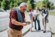 © qunica.com - A middle-aged man checks his smartphone while three colleagues chat in the background during a business outing.