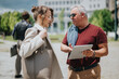 © qunica.com - A man and a woman have a business conversation outdoors while looking at a tablet. They discuss work details in an urban setting during a casual meeting.