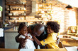 © Davor - Grandfather hugging two children in home kitchen