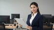 © Studicon - Confident young business woman holds a clipboard in an office setting