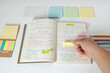© Maribel Falcon - Study setup with sticky notes and hand organizing information, highlighting productivity and learning process.