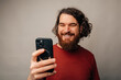 © Vulp - Man Looking At Phone With Warm Smile, Engaged By Message Or App Content, Casual Indoor Portrait, Modern Mobile