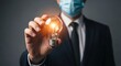 © Pixel Stone - Businessman in a suit and medical mask holding a glowing light bulb representing a creative idea