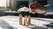 © Myimages - Life insurance concept showing family protection with wooden figures under umbrella on financial documents. Represents coverage, beneficiaries, income security, financial planning