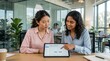 © ArtFocus Studio - Two diverse female professionals collaborating on a mobile app user flow design using a digital tablet in a modern corporate office