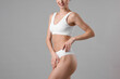 © New Africa - Smiling woman in underwear with slim body on grey background, closeup