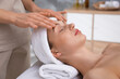 © New Africa - Beautiful woman in spa headband receiving facial massage in salon, closeup