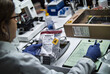 © digicomphoto - A police forensic expert is examining a mobile phone that is being used as evidence in a murder case