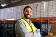 © fizkes - Portrait of smiling professional male worker stands in industrial warehouse or logistics facility with arms crossed, represents efficient operations, skilled labor, successful supply chain management
