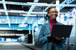 © DC Studio - Smiling data center female engineer configuring server settings with laptop software. Happy woman in modern high tech server hub using notebook to do maintenance tasks on infrastructure machines