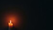 © Audax - Single lit candle against a dark, textured wall with copy space.
