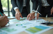 © Pete - Business people examine charts and graphs related to sustainability and green energy. Tiny wind turbine model sits on table near reports. Team discusses eco strategy.