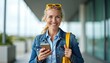 © Pete - Happy mature woman holds phone with yellow bag and sunglasses. Blond female smiles outdoor, wears denim jacket. Casual, relaxed, friendly, confident, lifestyle photo.