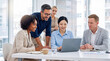© Athena Studio - Diverse team of business professionals collaboratively reviewing data on a laptop during an engaging meeting in.