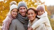 © Sonita - A happy family dressed in cozy sweaters, enjoying an autumn outing in a vibrant park.