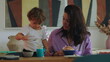 © Marco - Mother wiping toddler face and hands at breakfast table showing caring gesture and attentive parenting during everyday family routine at home