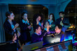 © ultramansk - Smiling corporate group applauding a late night project achievement. Professional IT developers and managers cheering around a glowing monitor in the workplace.