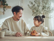 © ANGELINA - Father and daughter smiling while enjoying a cinnamon roll at home