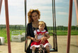 © Asya Molochkova/Stocksy - Mother and Child Sitting on Swing Outdoors