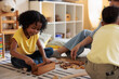 © Jovo Jovanovic/Stocksy - Children and adult play with wooden blocks on rug.