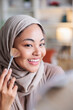 © Jovo Jovanovic/Stocksy - Smiling woman in hijab applies makeup with brush.
