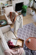 © Jovo Jovanovic/Stocksy - Woman in hijab examines new shirt in cozy living room.