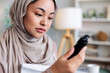 © Jovo Jovanovic/Stocksy - Woman in hijab examines a black object closely.