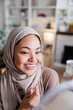 © Jovo Jovanovic/Stocksy - Smiling woman in hijab applies lip gloss.