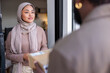 © Jovo Jovanovic/Stocksy - Woman in hijab receives package from delivery person.