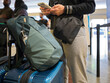 © Rowena Naylor/Stocksy - Checking Phone at the Airport Terminal