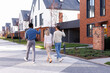 © Oleksii Syrotkin/Stocksy - Realtor and couple going, pointing and looking at townhouse complex