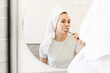 © Asya Molochkova/Stocksy - Woman Brushing Teeth with Towel on Head After Shower