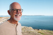 © Rob and Julia Campbell/Stocksy - Candid portrait of a smiling senior man by the sea