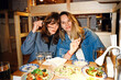 © Asya Molochkova/Stocksy - Two Women Enjoying Asian Food Together at Cozy Restaurant