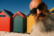 © Berena Alvarez/Stocksy - Bearded man posing at colorful beach huts in Muizenberg