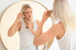 © Pixel-Shot - Young blonde man with spray combing hair near mirror in bathroom