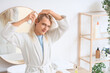 © Pixel-Shot - Young blonde man with hair spray in bathroom