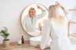 © Pixel-Shot - Young blonde man with hair spray near mirror in bathroom