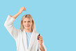 © Pixel-Shot - Young blonde man applying hair serum on blue background