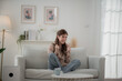 © surachetkhamsuk - Happy young woman watching TV and cheering on sofa at home.